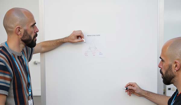 Álvaro Torres dibujando en una pizarra la pirámide con Hero, Hub y Help