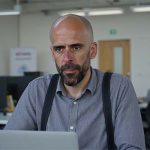 Álvaro Torres mirando su web en un portátil con gesto de duda