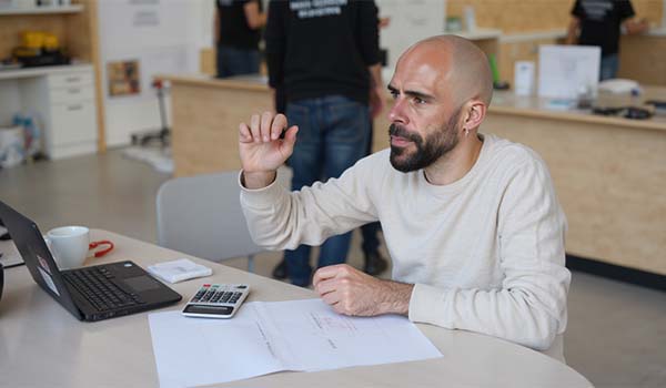 Álvaro Torres calculando costes en una libreta con una calculadora y un café