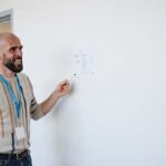 Álvaro Torres dibujando un flujo de conversación simple en una pizarra con flechas