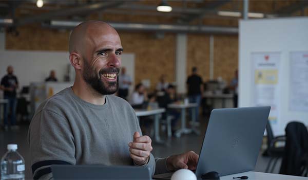 Álvaro Torres sonriendo mientras revisa en su portátil un gráfico con leads captados de madrugada