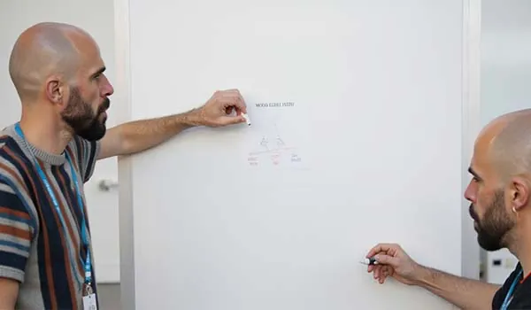 Álvaro Torres dibujando en una pizarra la pirámide con Hero, Hub y Help