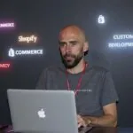 Álvaro Torres dudando entre WooCommerce, Shopify y un desarrollo a medida frente al portátil
