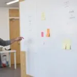 Álvaro Torres señalando un plan de contenidos en una pizarra con post-its